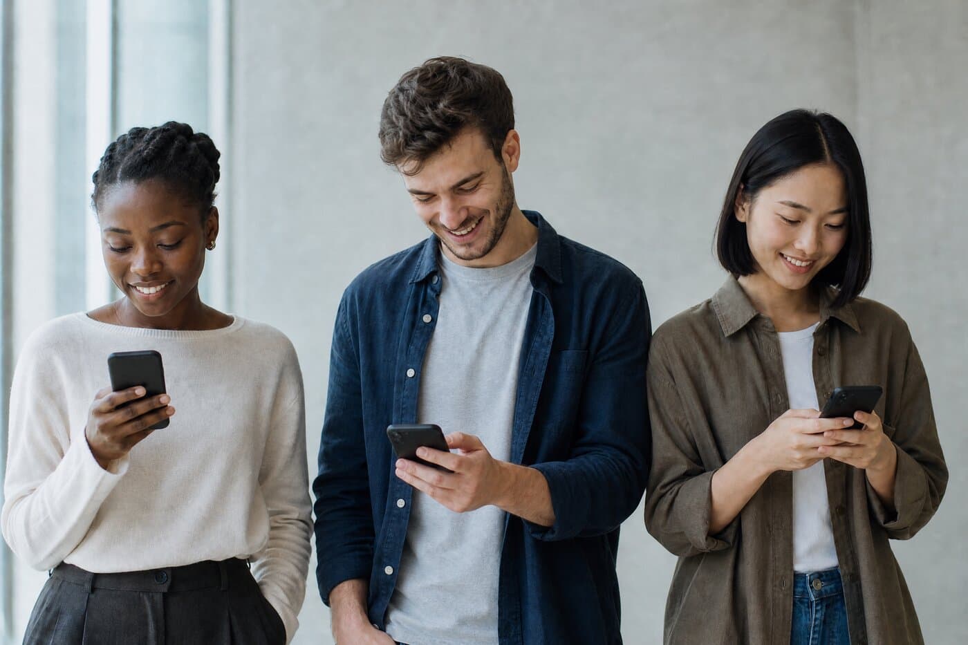 Un groupe de personnes d’horizons differents utilisant chacune son telephone